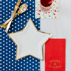 Fourth of July table set up with gold utensils and cream colored star shaped plate.